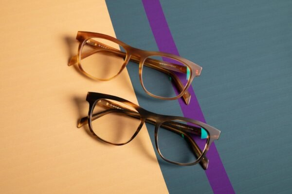 Close-up of two trendy spectacles on vibrant pastel surfaces.