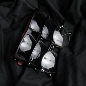Close-up of various stylish eyeglasses on black fabric, highlighting modern eyewear design.