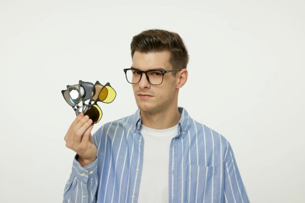Young male model wearing glasses and a striped shirt, showcasing various eyewear lenses.